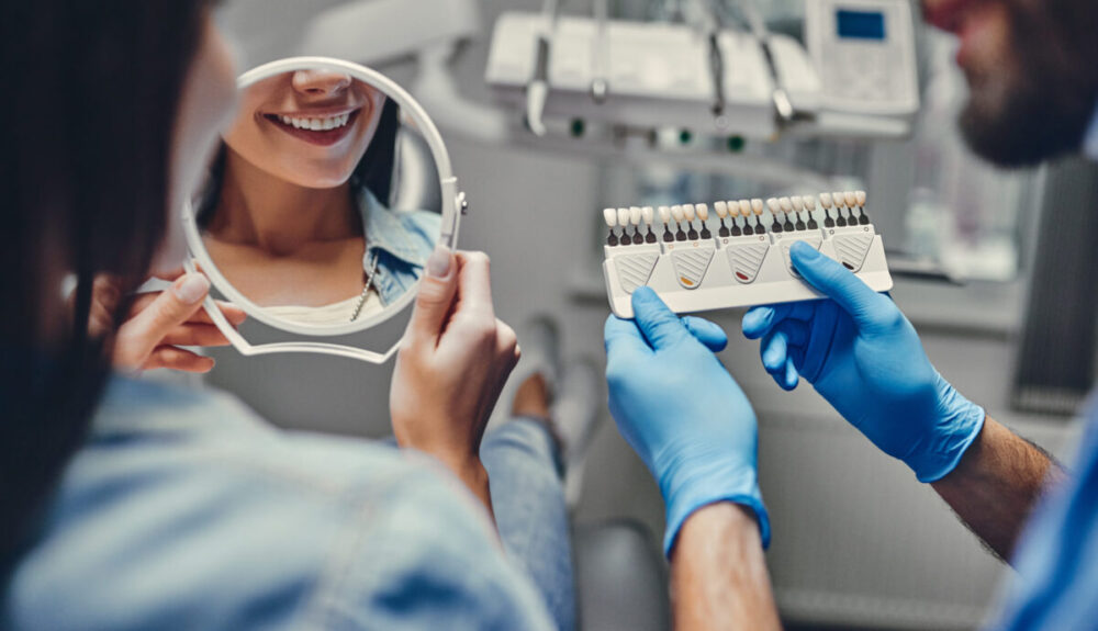 Attractive young woman in stomatology clinic with male dentist. Healthy teeth concept.